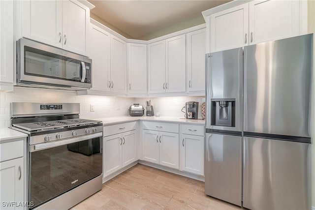 kitchen with light wood-style flooring, light countertops, white cabinets, appliances with stainless steel finishes, and tasteful backsplash