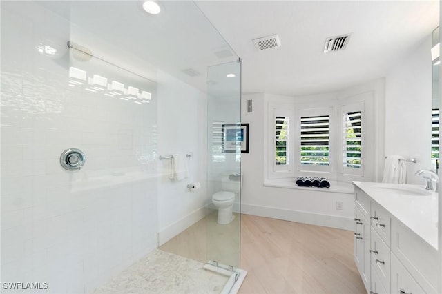 full bath featuring vanity, a walk in shower, visible vents, and baseboards