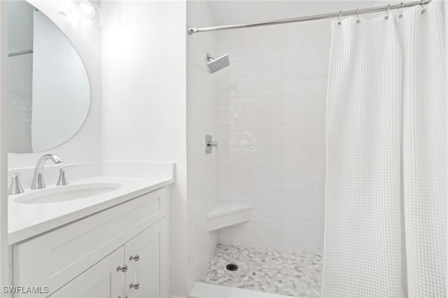 bathroom with tiled shower and vanity