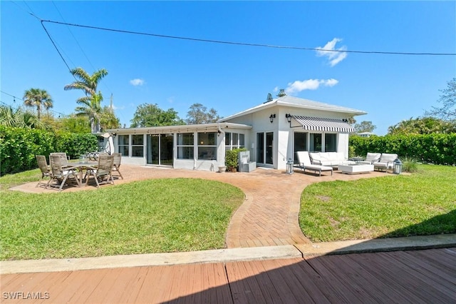 rear view of property with a patio area, a lawn, an outdoor hangout area, and a sunroom