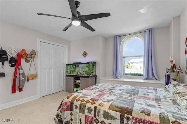 tiled bedroom with a closet, baseboards, and ceiling fan