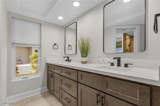 full bath featuring a sink, baseboards, double vanity, and tile patterned flooring