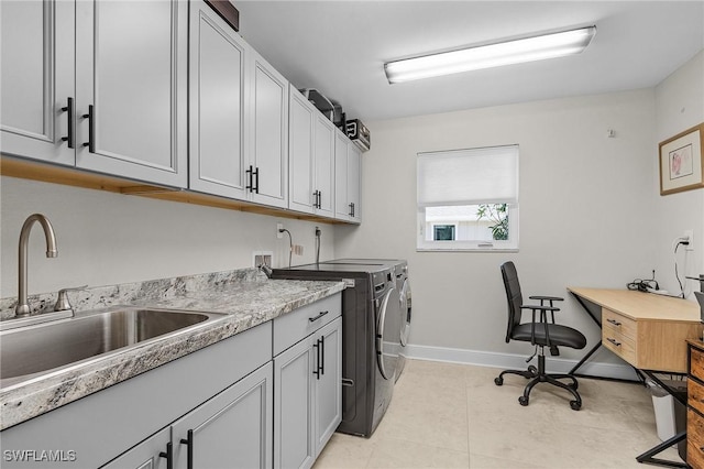 laundry room featuring light tile patterned floors, baseboards, cabinet space, separate washer and dryer, and a sink