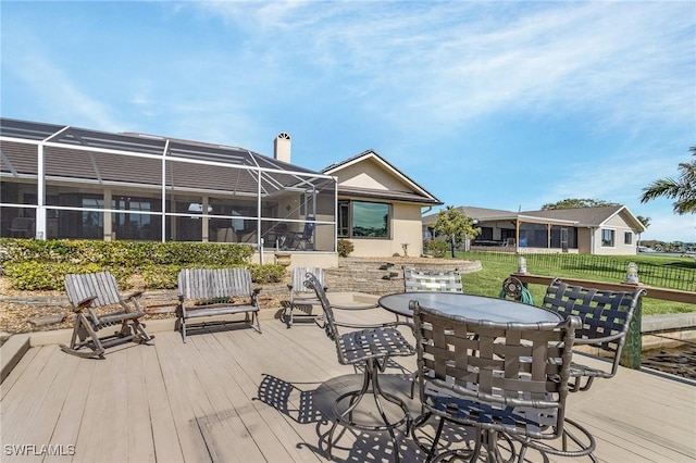 wooden deck featuring a lanai, outdoor dining area, and fence