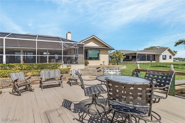 deck featuring a lanai, outdoor dining area, fence, and a yard