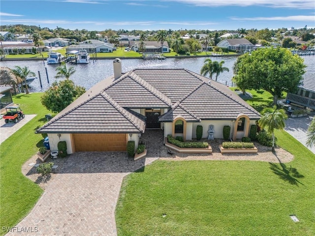 view of front of house featuring a front lawn, a water view, a tiled roof, decorative driveway, and a residential view