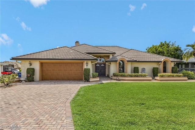 view of front facade featuring a chimney, a front lawn, a garage, a tiled roof, and decorative driveway