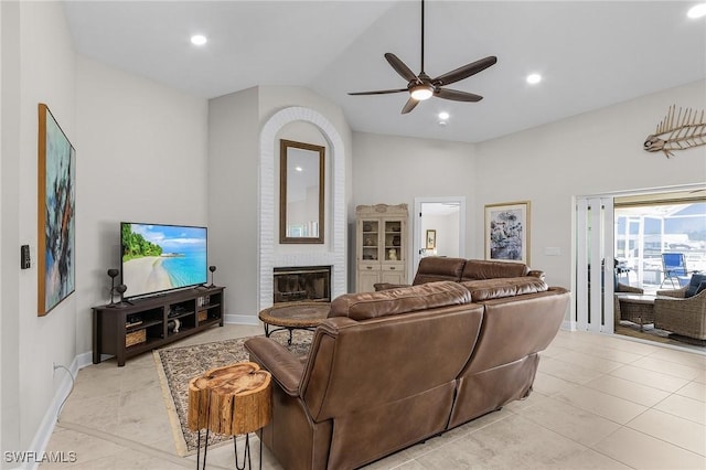 living room with recessed lighting, light tile patterned floors, lofted ceiling, a brick fireplace, and ceiling fan