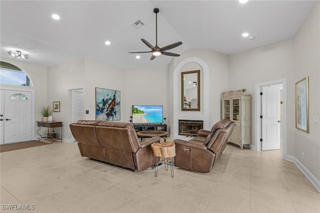 living room with visible vents, high vaulted ceiling, a ceiling fan, baseboards, and a brick fireplace