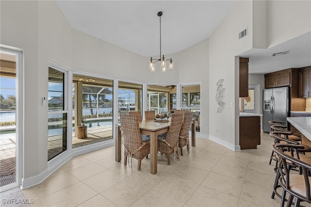 dining room featuring light tile patterned floors, visible vents, baseboards, and high vaulted ceiling