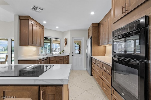 kitchen featuring light stone counters, light tile patterned floors, visible vents, a sink, and black appliances