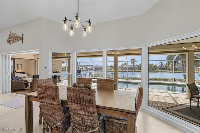 dining room featuring light tile patterned floors, high vaulted ceiling, an inviting chandelier, and a water view