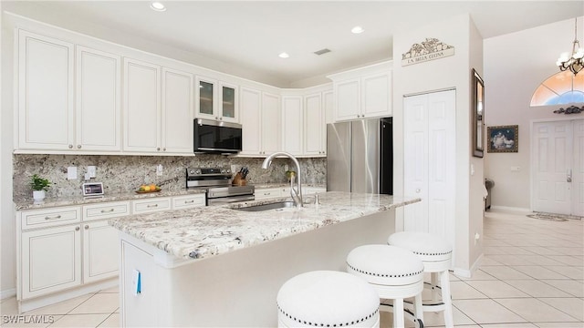 kitchen with light tile patterned flooring, tasteful backsplash, appliances with stainless steel finishes, and a sink