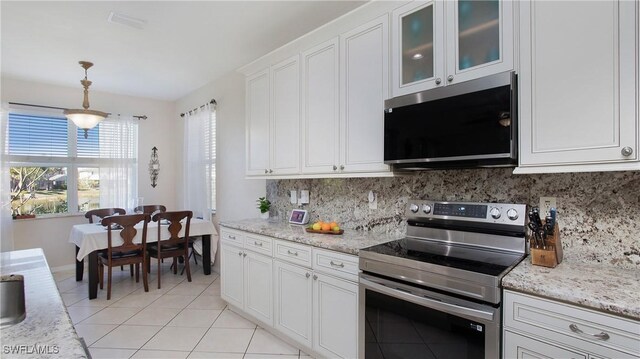 kitchen featuring electric stove, decorative light fixtures, white cabinetry, light tile patterned floors, and decorative backsplash