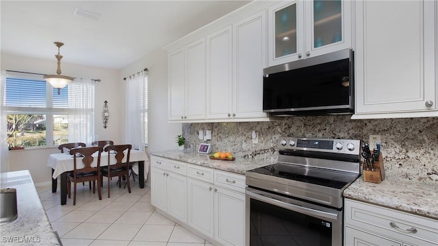 kitchen featuring light tile patterned flooring, backsplash, pendant lighting, white cabinets, and electric range