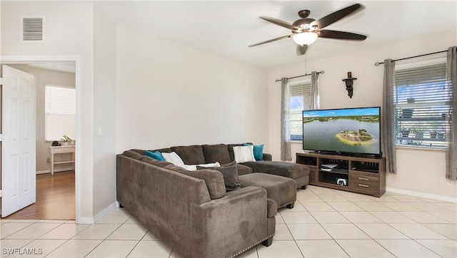 living room featuring light tile patterned floors, visible vents, baseboards, and a ceiling fan