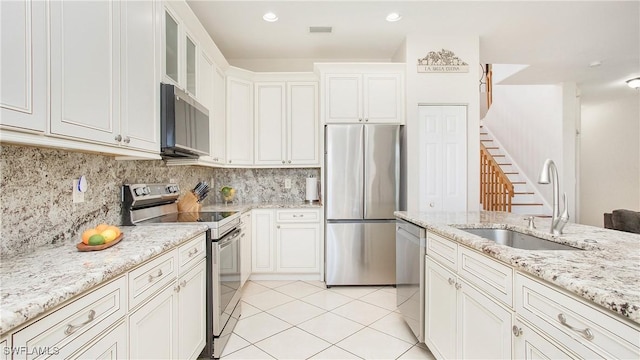 kitchen with light tile patterned floors, a sink, appliances with stainless steel finishes, and decorative backsplash