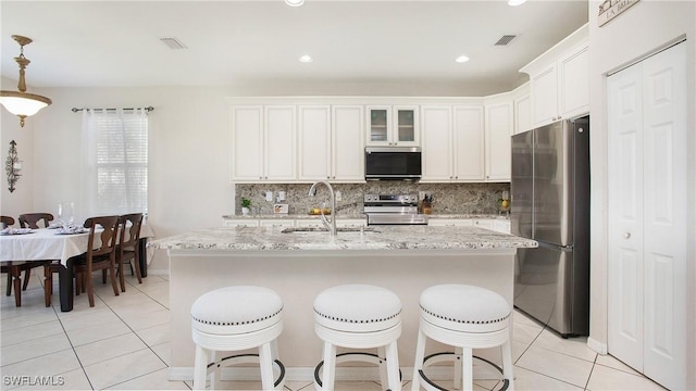 kitchen with light tile patterned flooring, visible vents, stainless steel appliances, and decorative backsplash