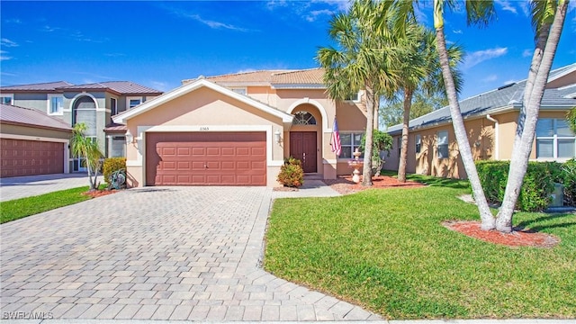 view of front facade with stucco siding, decorative driveway, an attached garage, and a front lawn