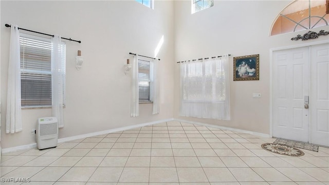 foyer featuring light tile patterned floors, a high ceiling, and baseboards