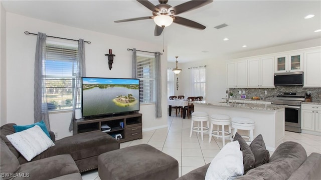 living area with light tile patterned flooring, ceiling fan, visible vents, and recessed lighting
