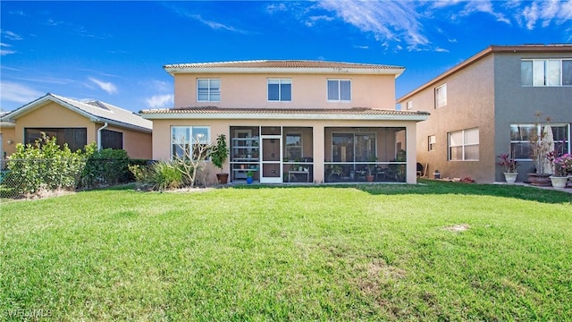 rear view of property featuring stucco siding, a tiled roof, a yard, and a sunroom