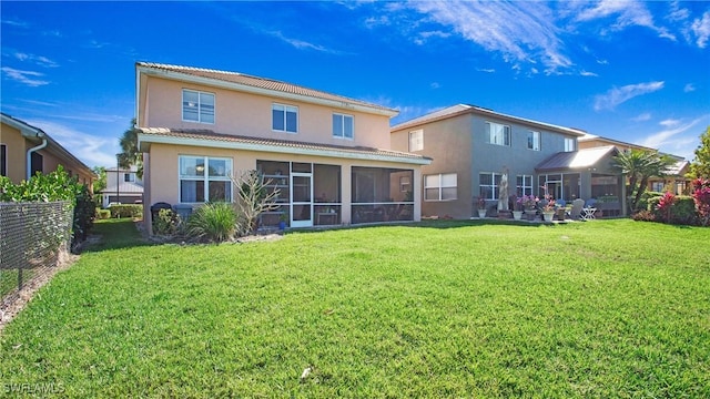 rear view of property with a sunroom, stucco siding, fence, and a lawn