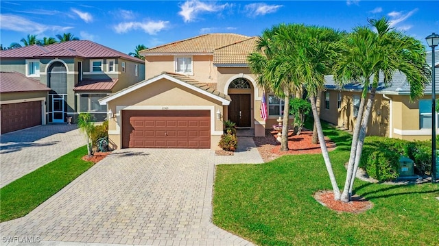 view of front of house featuring a front lawn, a tiled roof, stucco siding, decorative driveway, and a garage