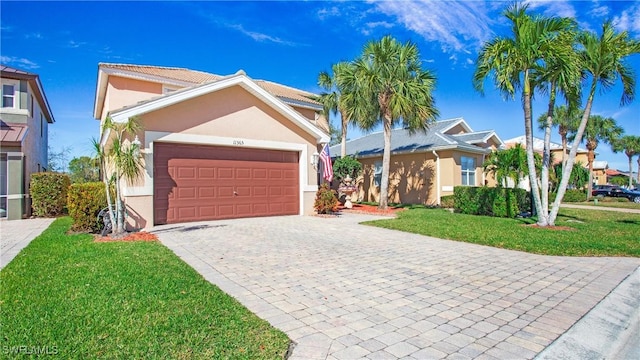 view of front facade with a front lawn, decorative driveway, a garage, and stucco siding