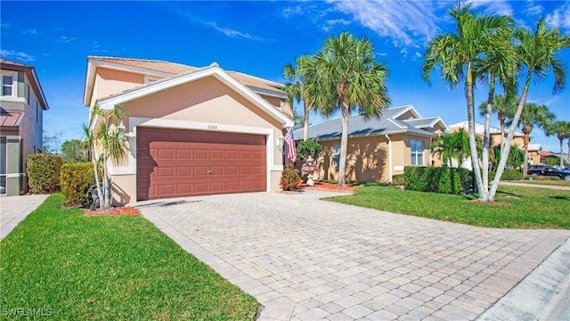 view of front of property featuring a front lawn, decorative driveway, stucco siding, and a garage