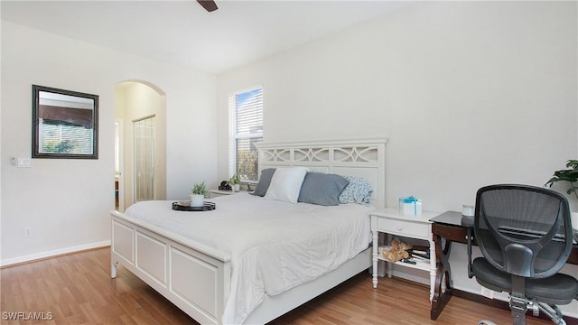 bedroom with baseboards, arched walkways, and wood finished floors