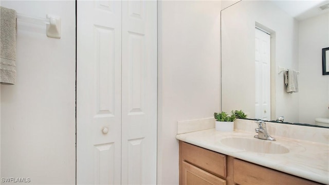 bathroom with vanity, toilet, visible vents, and a closet