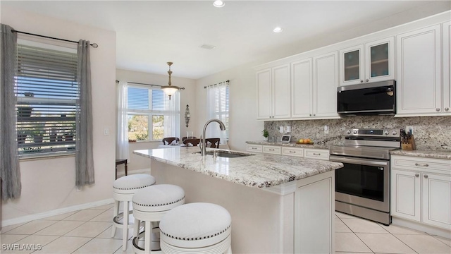 kitchen with light tile patterned flooring, decorative backsplash, stainless steel electric range oven, and a sink