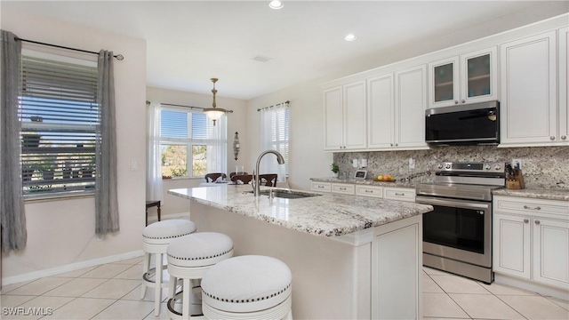 kitchen featuring light tile patterned flooring, electric stove, a sink, and tasteful backsplash
