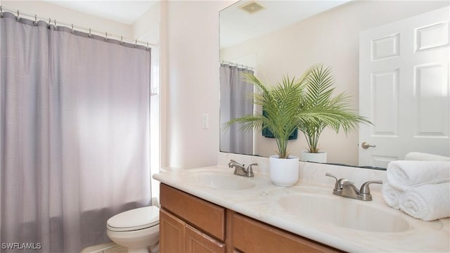 bathroom featuring double vanity, visible vents, toilet, and a sink