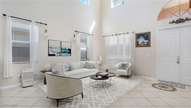 living room with plenty of natural light, baseboards, a high ceiling, and light tile patterned floors