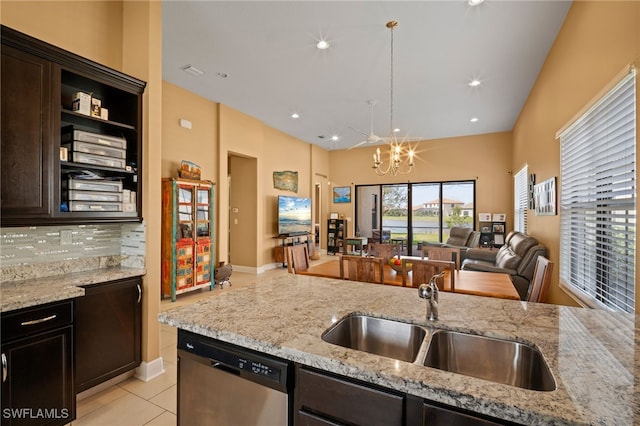 kitchen featuring tasteful backsplash, dishwasher, open floor plan, light stone countertops, and a sink