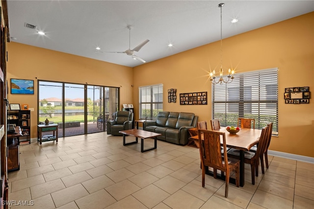 dining room with light tile patterned floors, baseboards, visible vents, a towering ceiling, and ceiling fan with notable chandelier