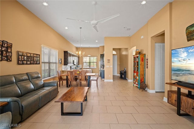 living area featuring ceiling fan with notable chandelier, baseboards, and light tile patterned floors