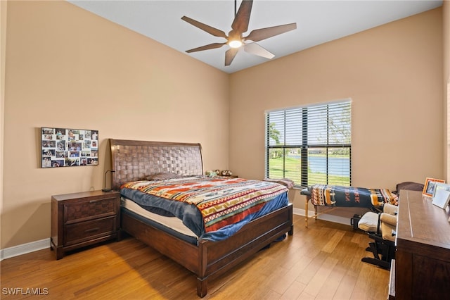 bedroom with light wood-type flooring, ceiling fan, and baseboards