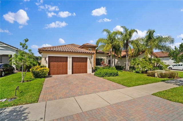 mediterranean / spanish-style home with decorative driveway, a tiled roof, a front lawn, and stucco siding