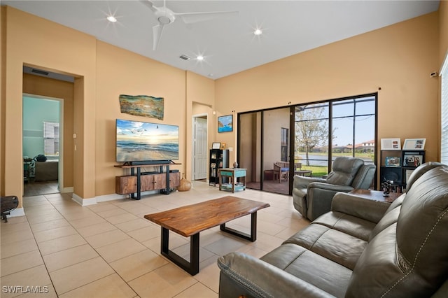 living room with visible vents, a towering ceiling, light tile patterned flooring, ceiling fan, and baseboards