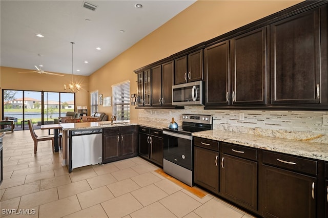 kitchen with stainless steel appliances, visible vents, backsplash, open floor plan, and light stone countertops