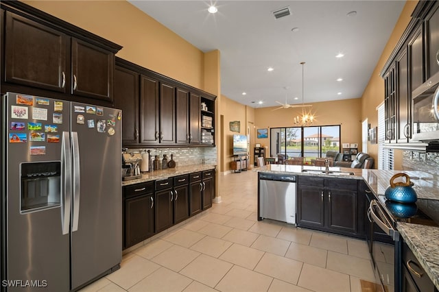 kitchen featuring stainless steel appliances, a sink, visible vents, open floor plan, and tasteful backsplash