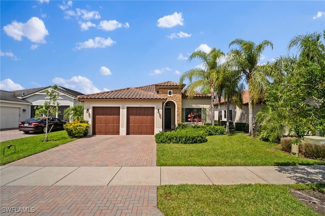 mediterranean / spanish house featuring a garage, stucco siding, a tiled roof, decorative driveway, and a front yard