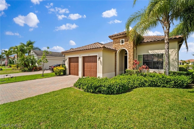 mediterranean / spanish house with an attached garage, stone siding, decorative driveway, stucco siding, and a front yard