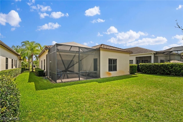 back of house featuring glass enclosure, a lawn, a tiled roof, and stucco siding