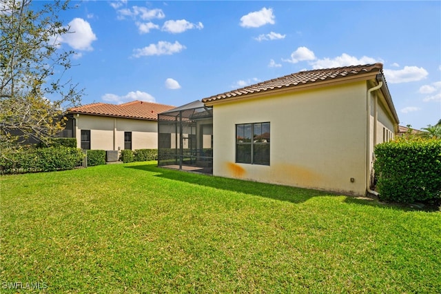 back of property with a lanai, a lawn, a tiled roof, and stucco siding