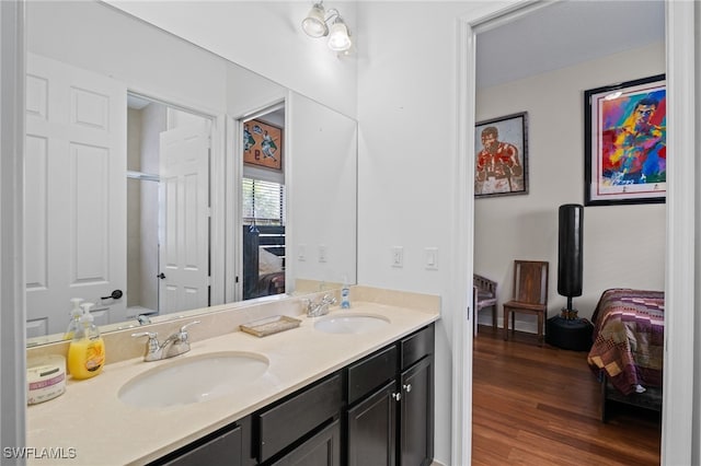 ensuite bathroom featuring connected bathroom, a sink, and wood finished floors