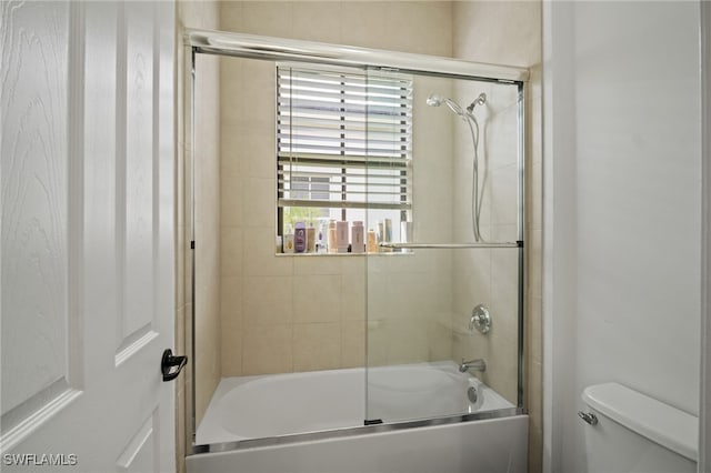 bathroom with toilet and shower / bath combination with glass door